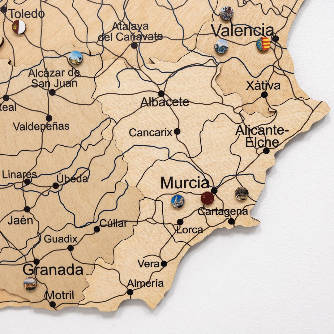 Wooden Spain wall map in gold with raised city names, route lines, and small pins.