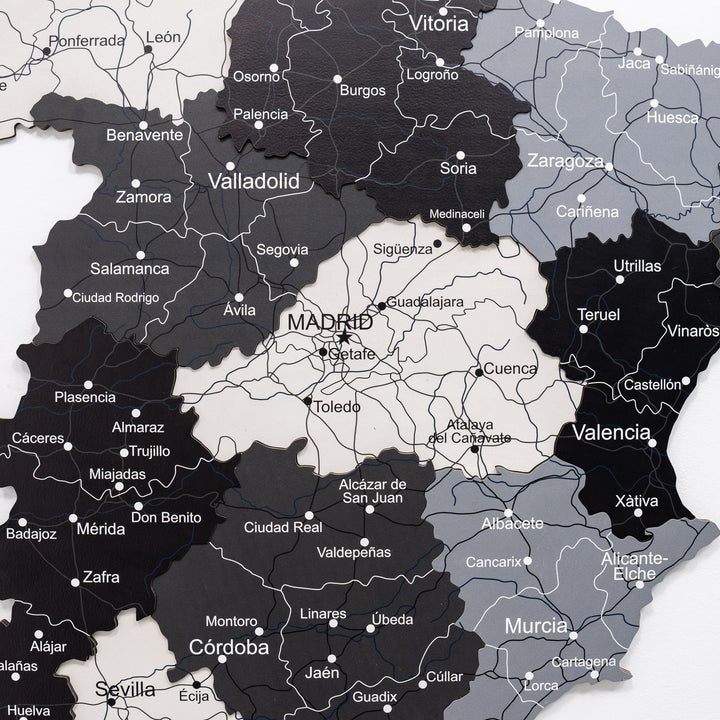 Close-up of wooden Spain wall map with dark and light regions plus printed town names