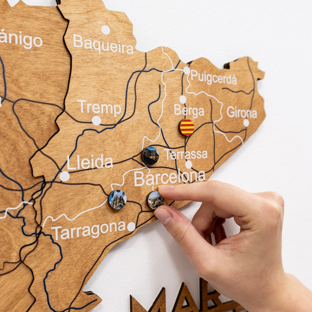 Oak wooden Spain map with raised borders and a hand placing circular decorative markers
