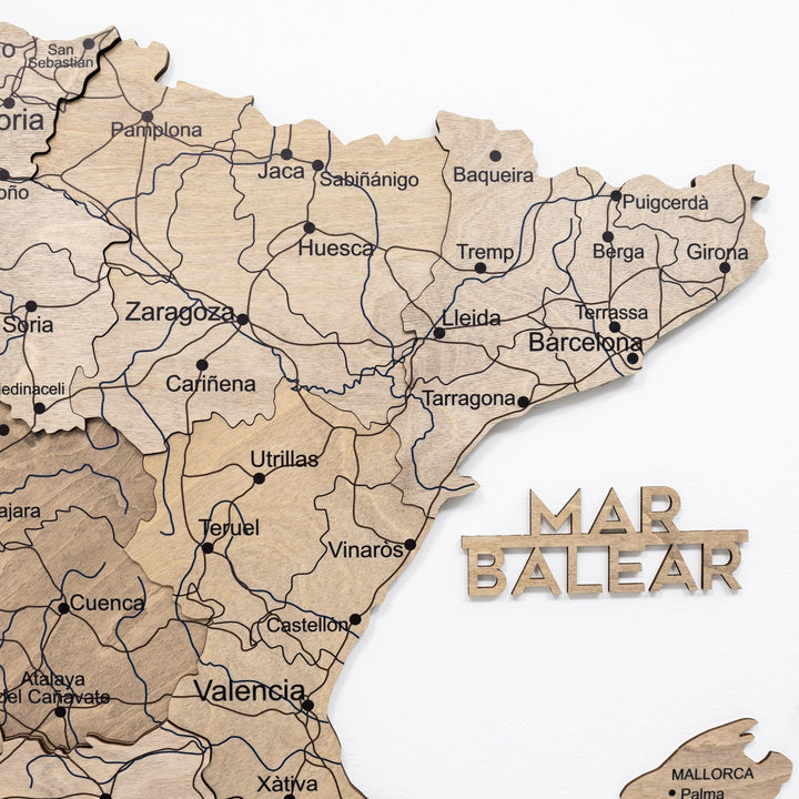 Wooden Spain map with carved coastal names, region outlines, and colored push pins
