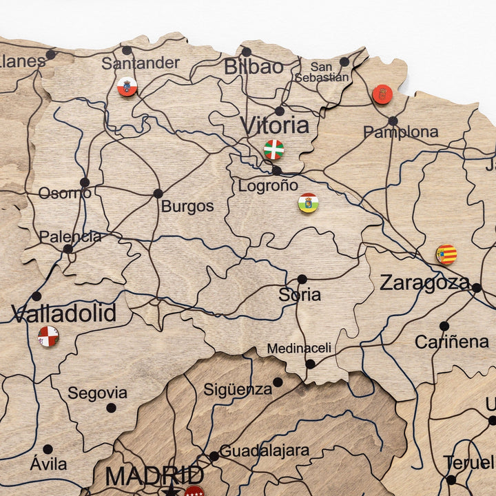 Wooden Spain map close-up with town names, region borders, and small flag icons