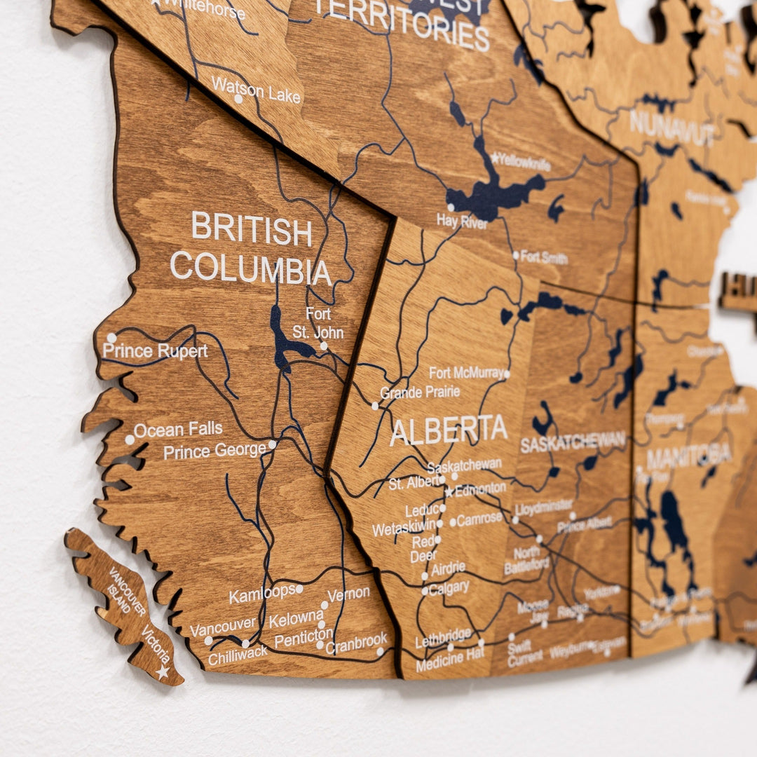 Close-up of wooden Canada wall map with engraved province names and blue inlaid waterways