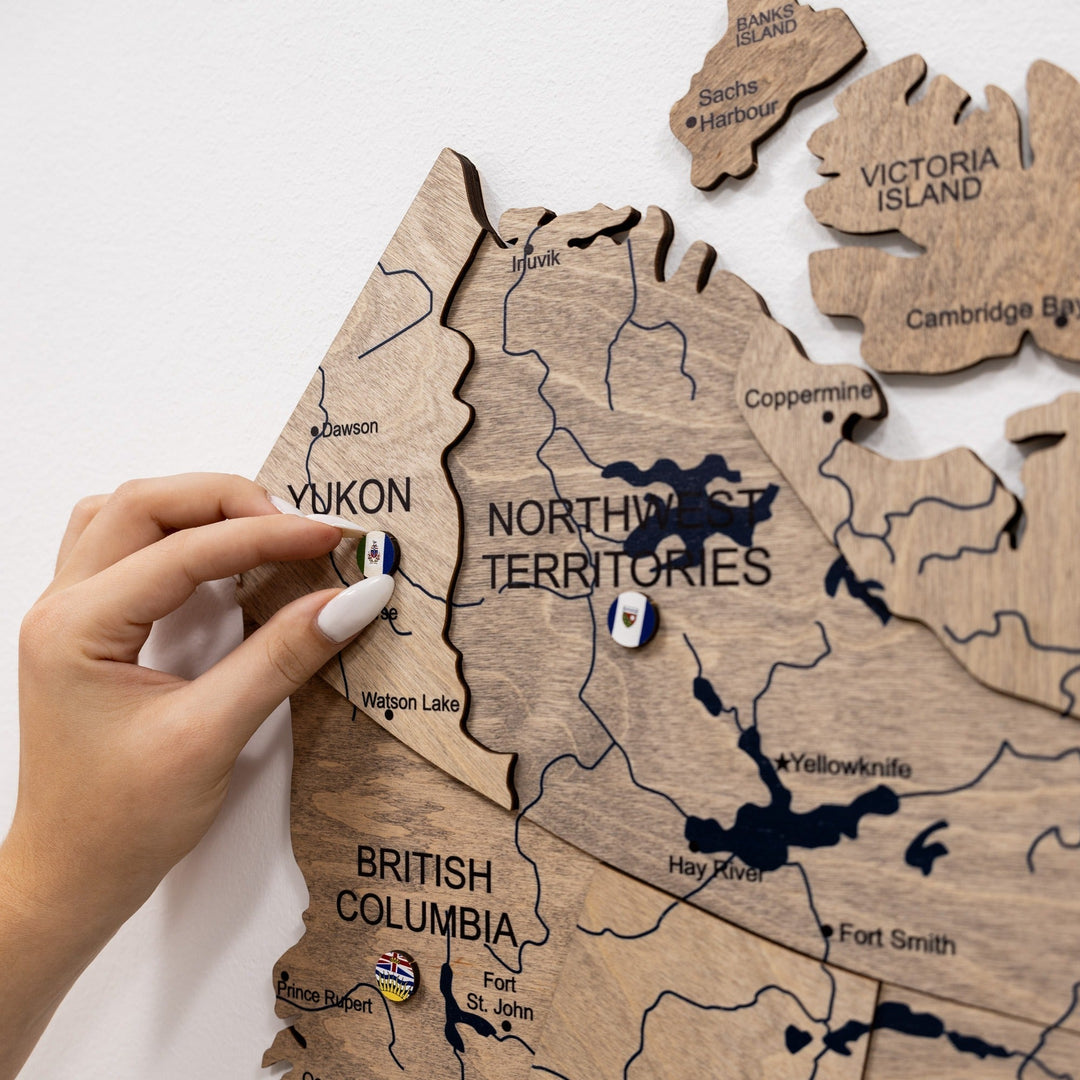 Wooden Canada map wall decor with small souvenir pins on the Yukon and Northwest Territories.
