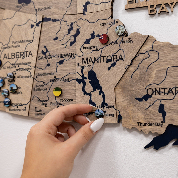 Wooden 3D Canada map segment with city and lake labels, held by hand
