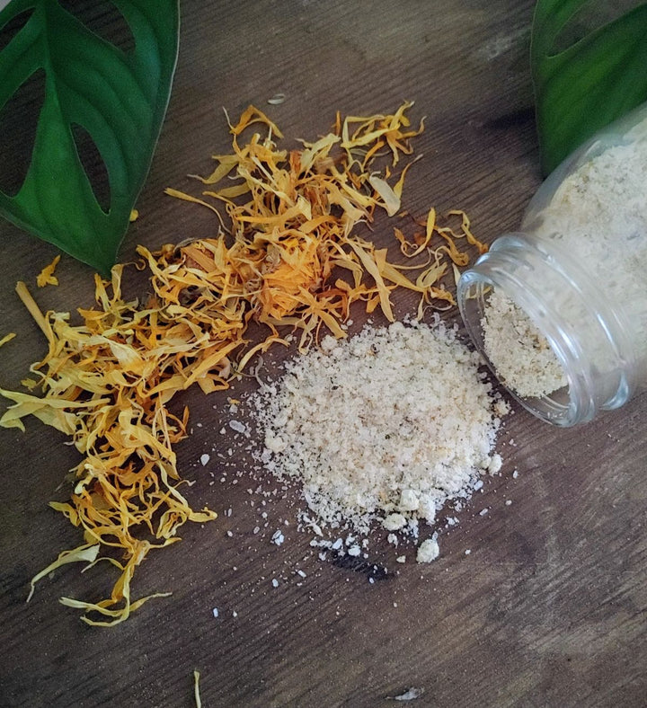 Bath soak blend with white salts and dried yellow botanicals, with small glass jar