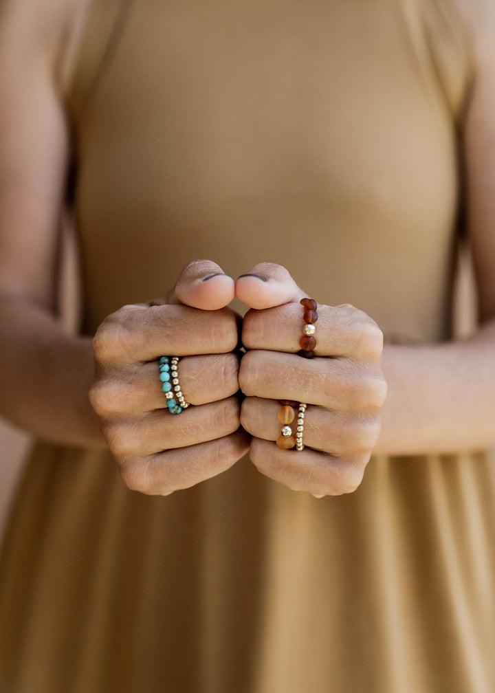 Turquoise and gold bead rings stacked on fingers