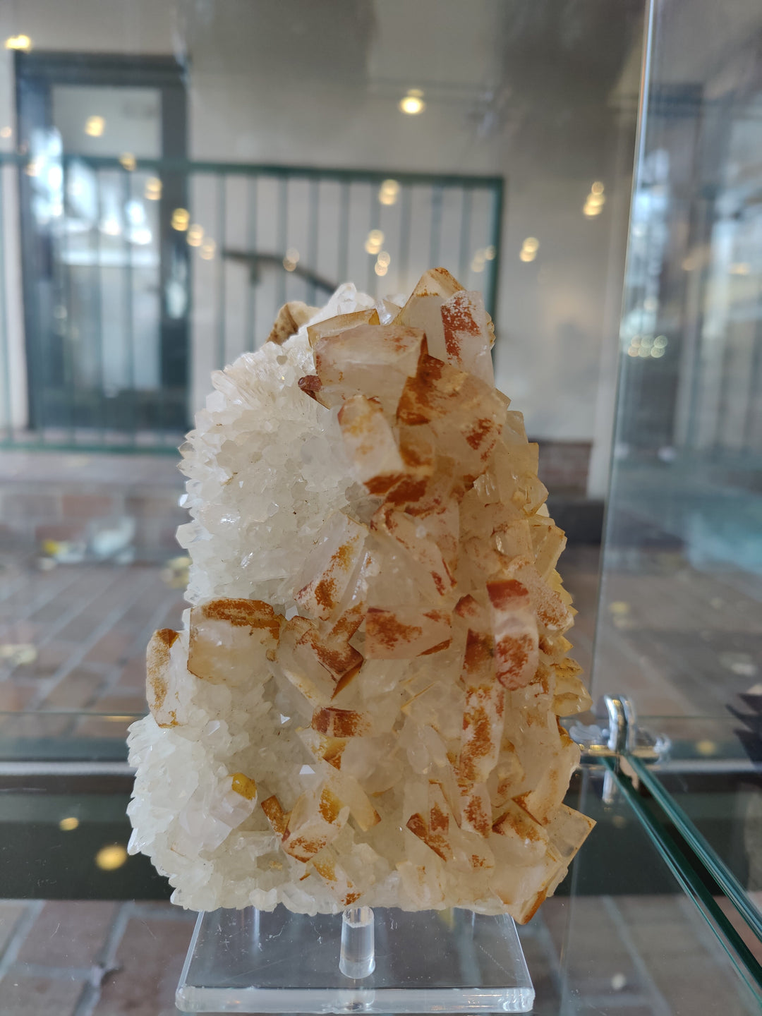 Large orange barite crystals on white quartz specimen on clear stand