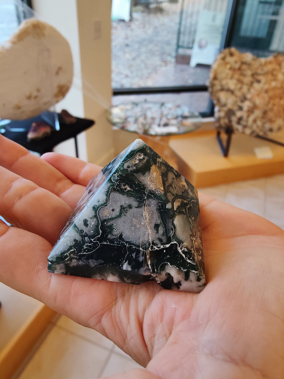Moss agate pyramid stone in hand, dark green with white streaked veining