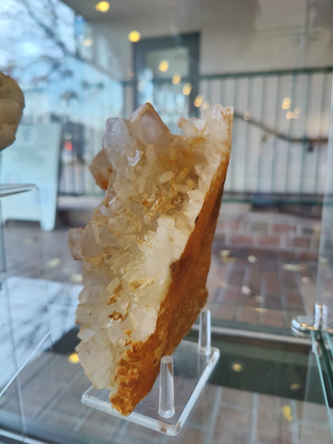 Orange barite and white quartz crystal cluster specimen on clear display stand
