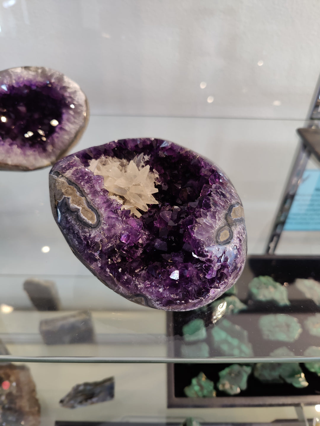 Amethyst geode sculpture with purple crystal cavity and pale calcite cluster, oval cut