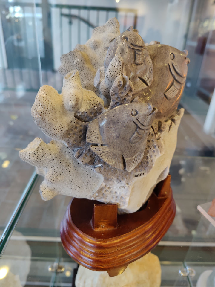 Coral reef fish life stone carving showing fish silhouettes over coral base on stand