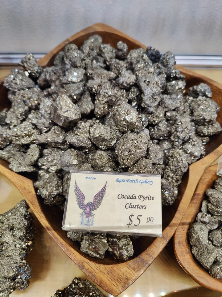 Pyrite crystal cluster specimen with bright metallic gray crystals on a wooden tray