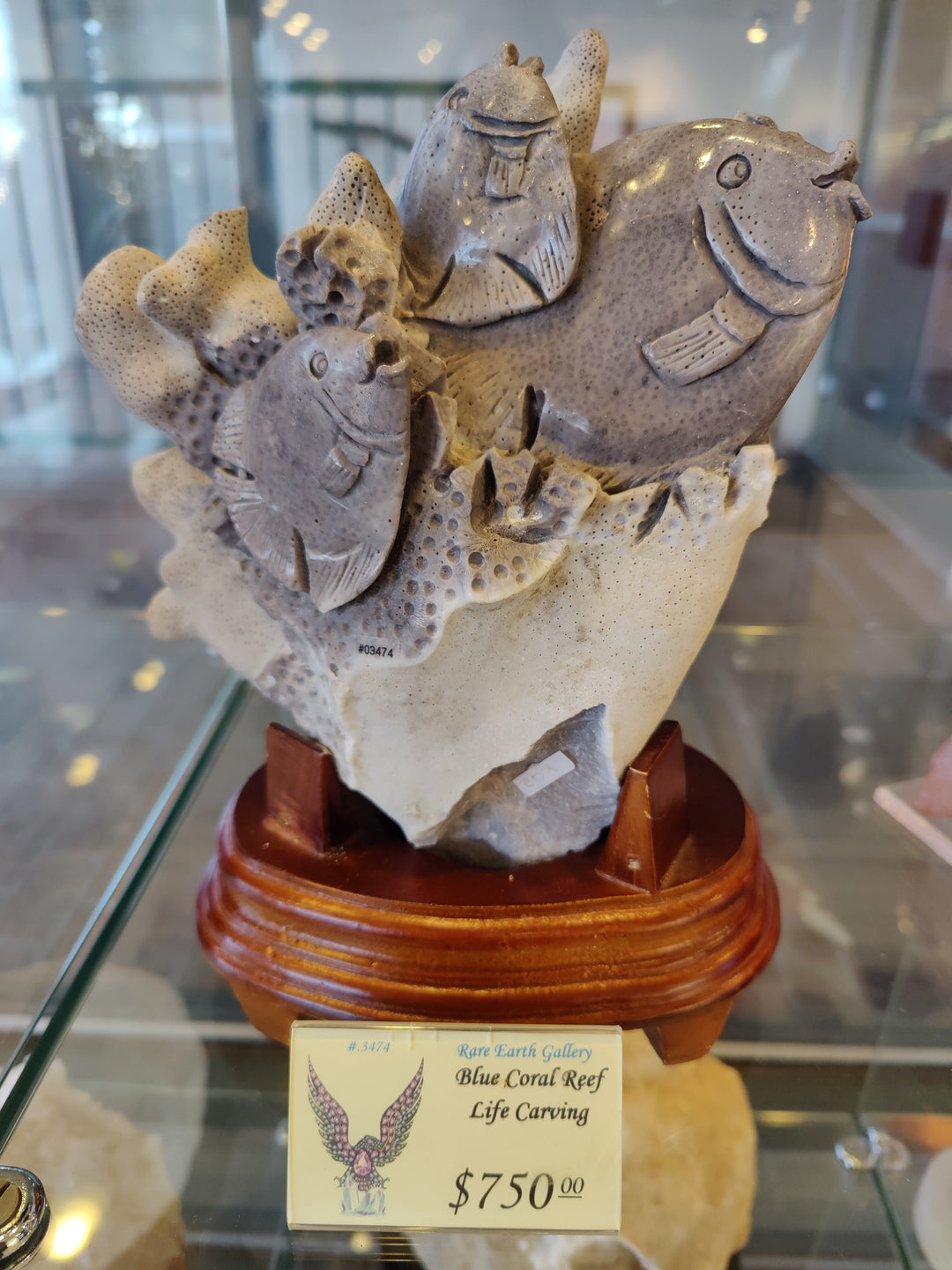 Coral reef fish life stone carving with several fish on a coral base, on stand
