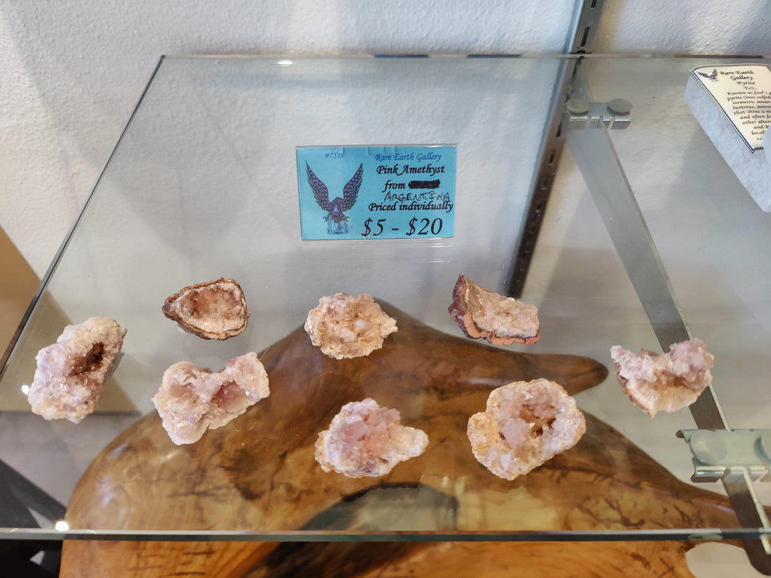 Pink amethyst crystal specimen display with several rough pink and purple clusters