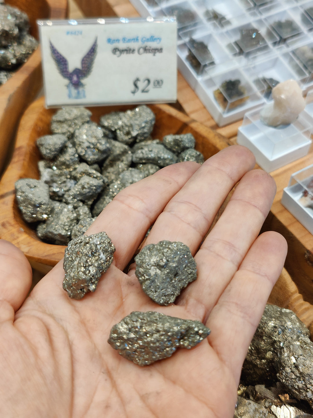 Dark gray pyrite ore nuggets held in an open hand