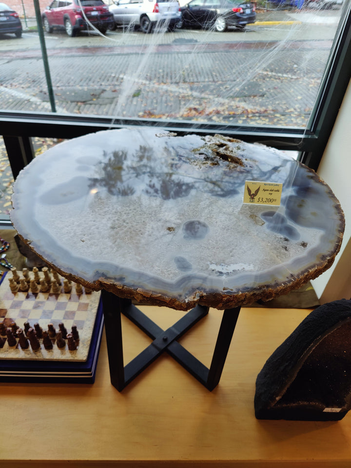 Large round agate quartz slab with light blue-gray surface and scattered dark inclusions