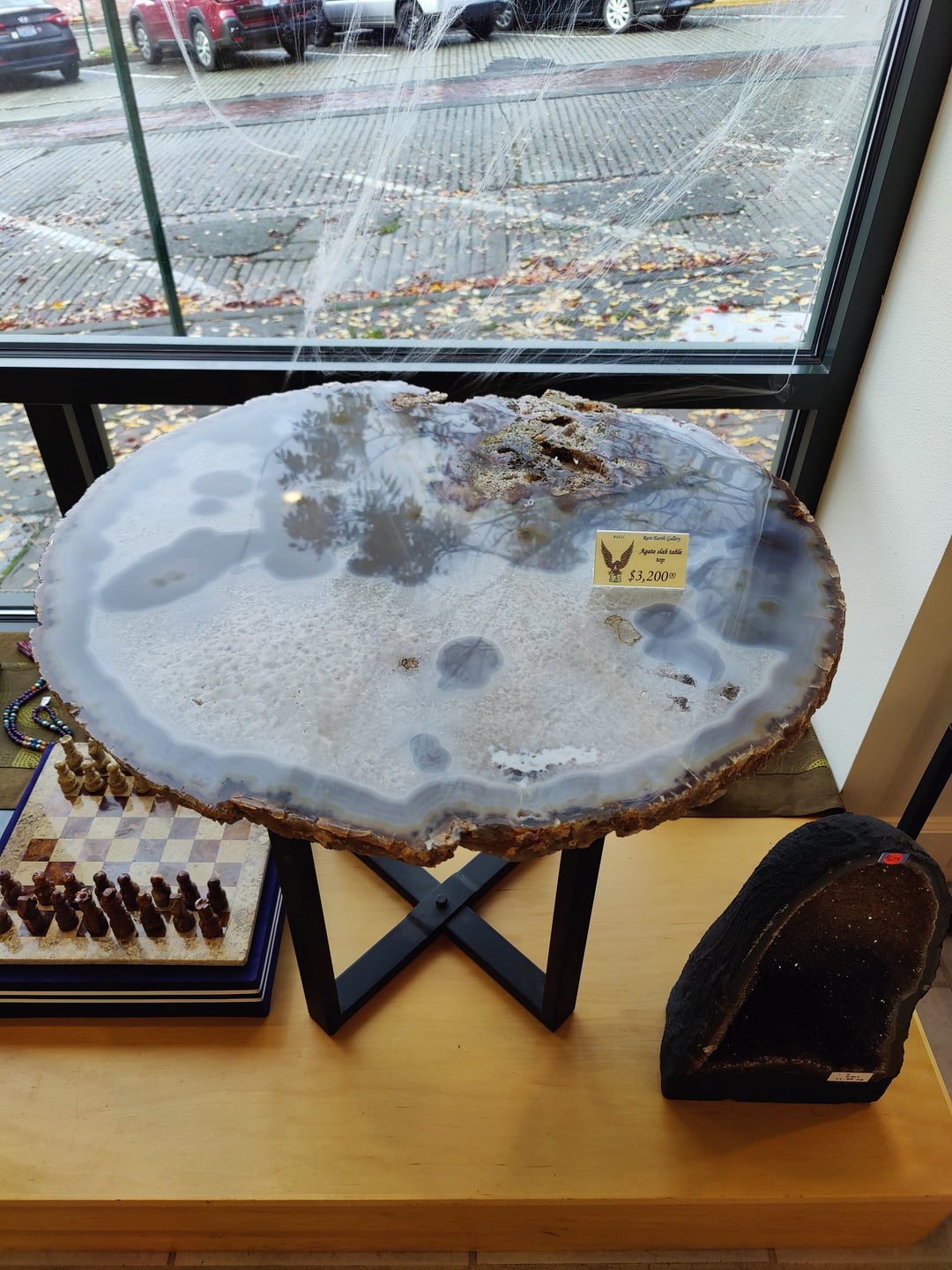 Large agate quartz slab with pale blue-gray pools and rough brown edge on X-stand