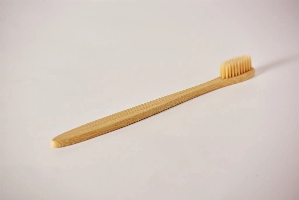 Bamboo toothbrush at a diagonal with soft bristles on light wooden head
