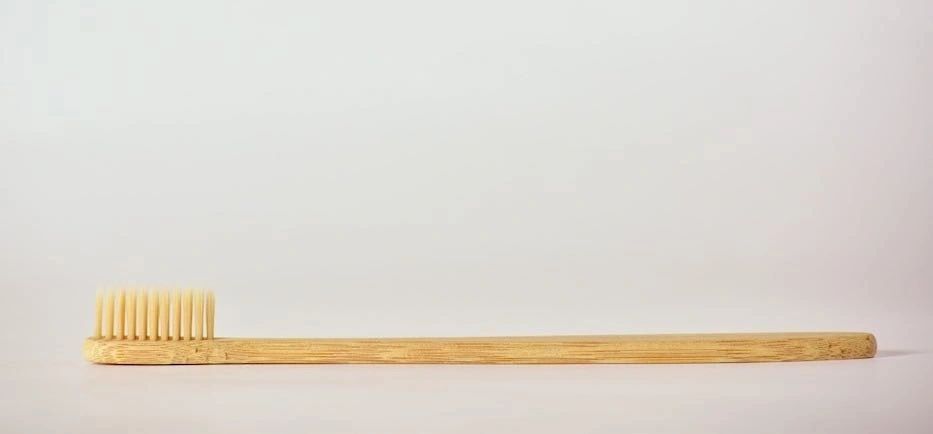 Bamboo toothbrush lying flat, soft bristles at one end