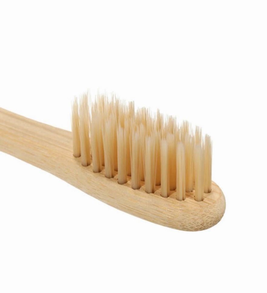 Toothbrush with dense soft bristles on light wood head and bamboo handle