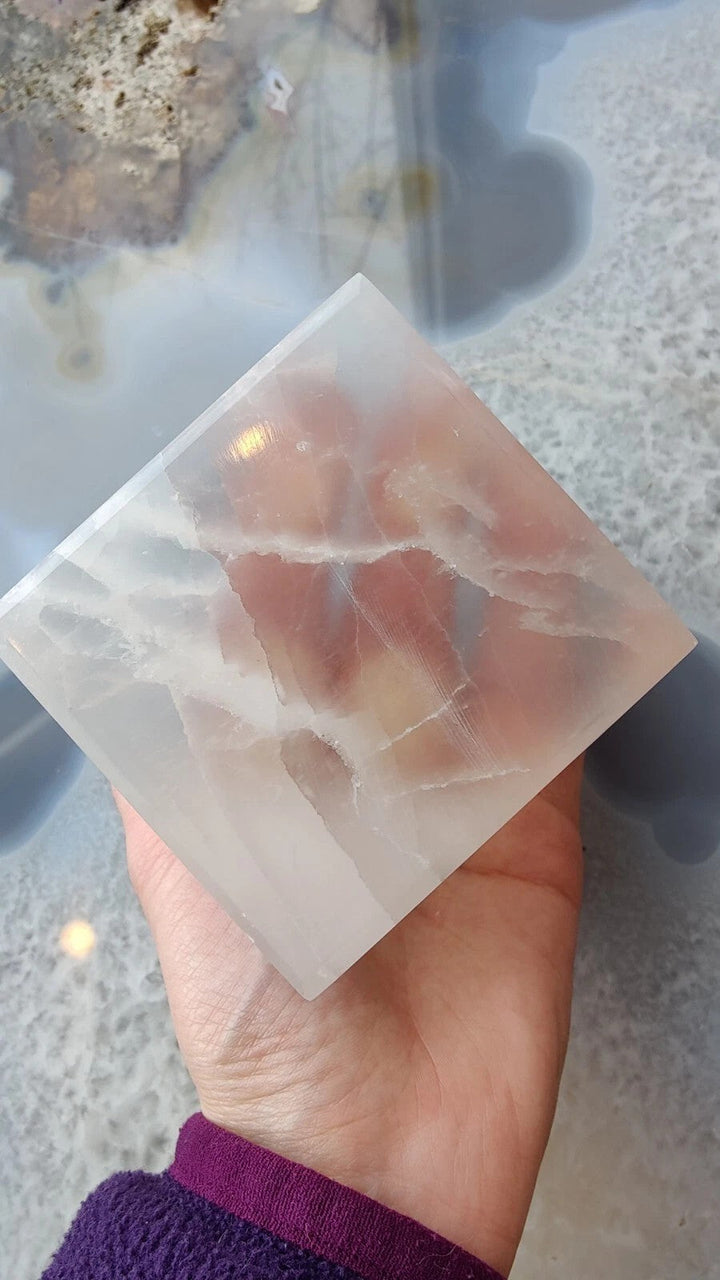 Translucent selenite cube, faceted edges visible in hand close-up.