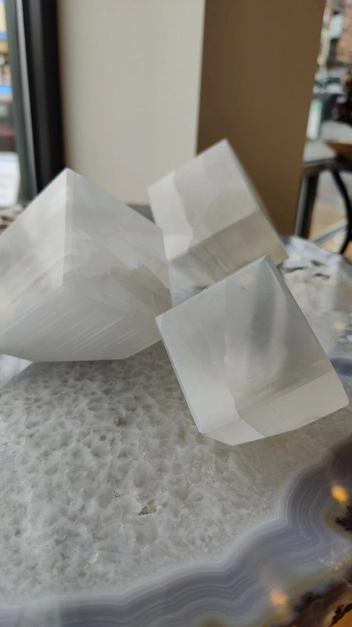 Set of translucent selenite standing cubes, faceted white blocks on display.