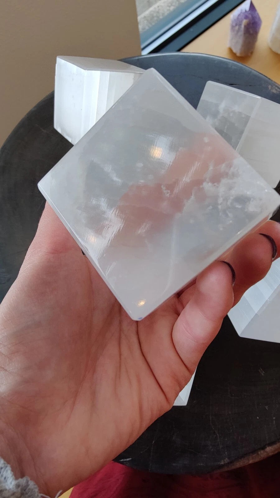 Translucent selenite cube with glossy facets, held close to camera