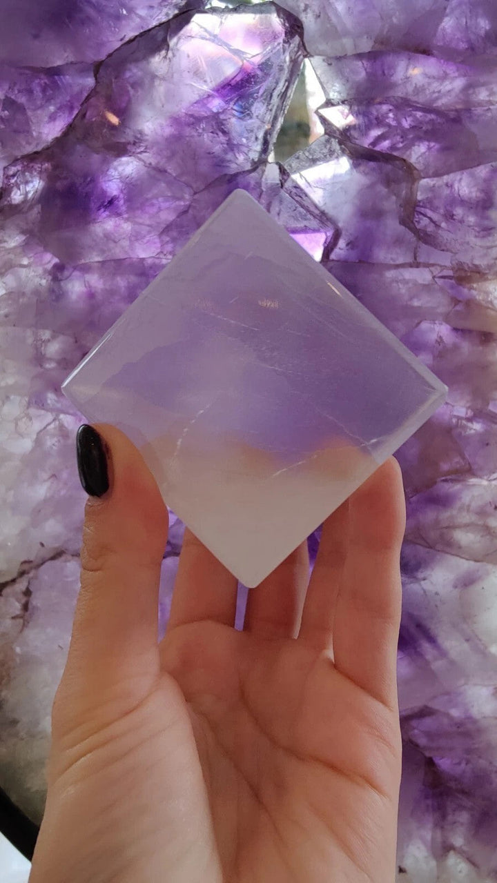 Translucent selenite standing cube with beveled edges, held in hand