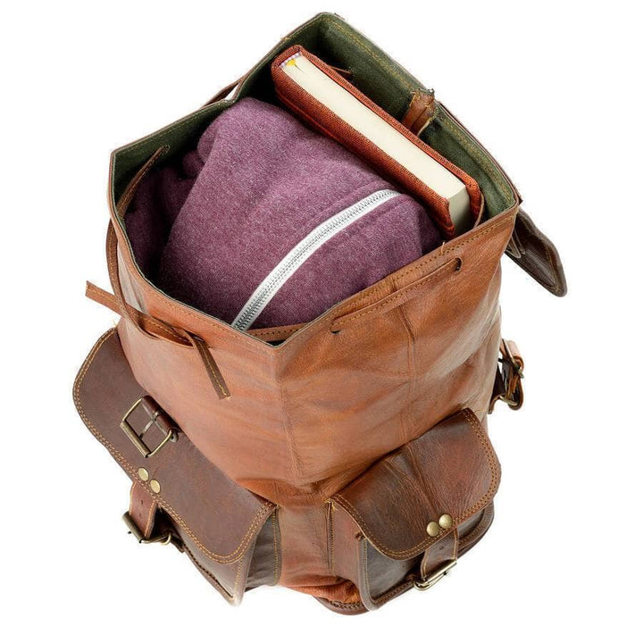 Open brown leather backpack with inner compartment holding a book and fabric pouch