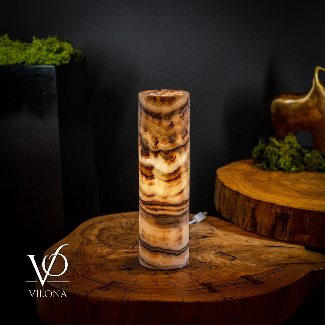 Sahara onyx cylinder table lamp with dark and light amber wave patterns, white plug