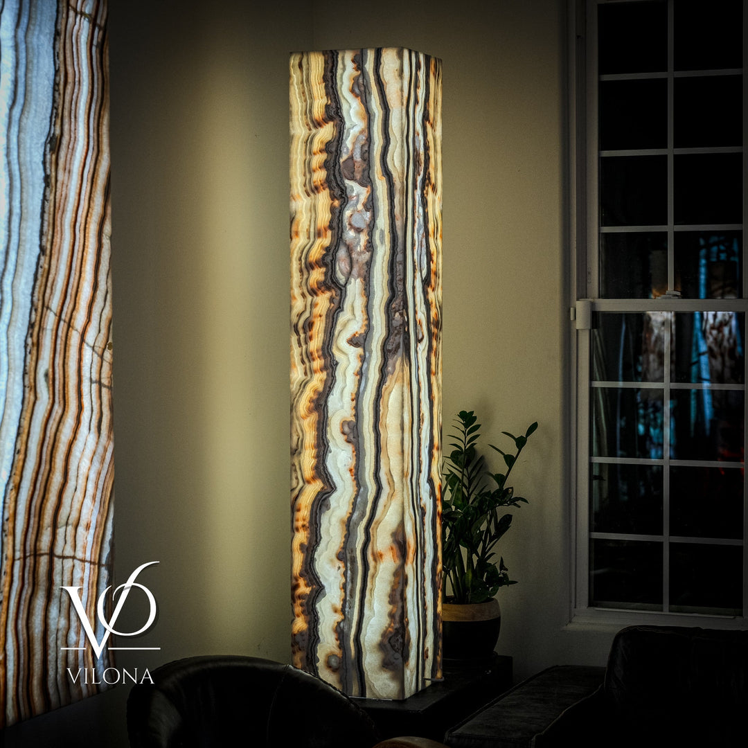 Tall square onyx floor lamp with vertical cream, blue, and amber veining on dark stand.