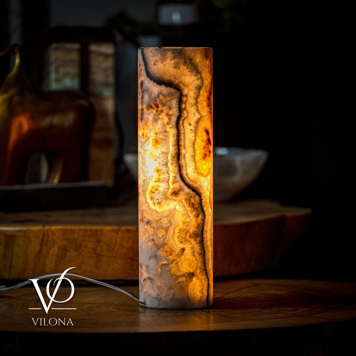 Cylindrical table lamp with amber onyx-style swirls and glowing interior