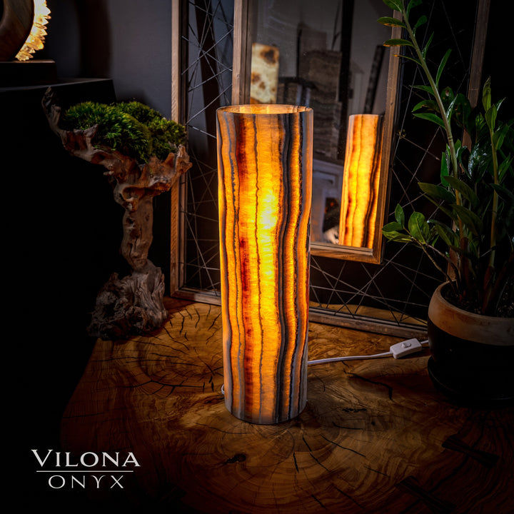 Onyx cylinder table lamp with warm amber glow and vertical striated pattern inside.