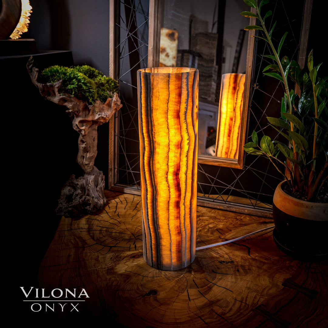 Onyx cylinder table lamp with vertical amber striations and warm glow in the front.