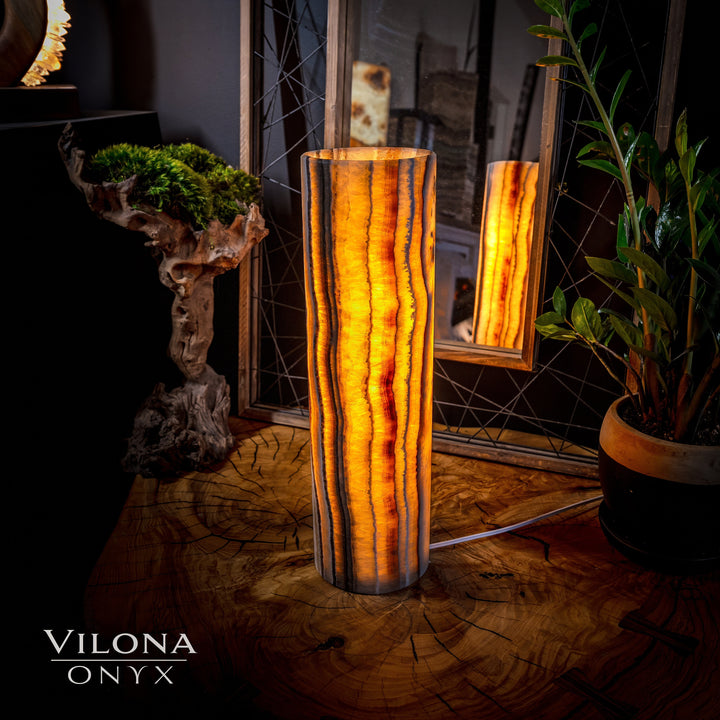 Onyx cylinder table lamp with vertical amber striations and warm glow in the front.