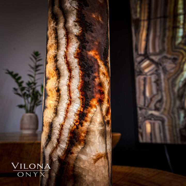 Onyx cylinder table lamp close-up with dark stone and glowing amber vein lines.
