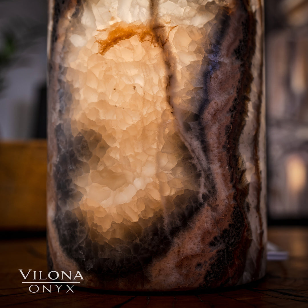 Onyx cylinder table lamp detail with speckled stone texture and warm interior light.