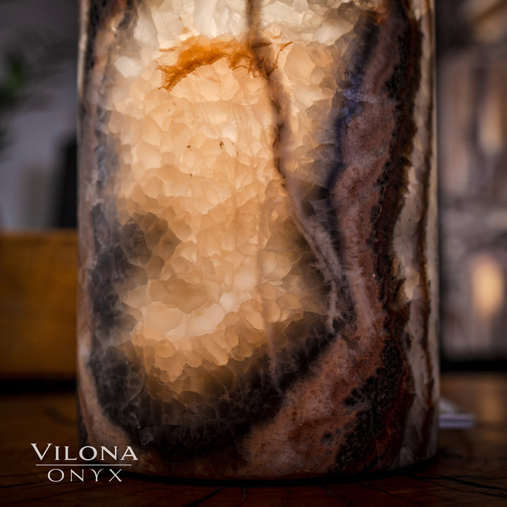 Onyx cylinder table lamp detail with speckled stone texture and warm interior light.