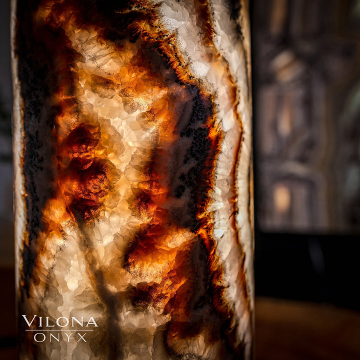 Onyx cylinder table lamp detail showing textured stone and bright amber glow streaks.