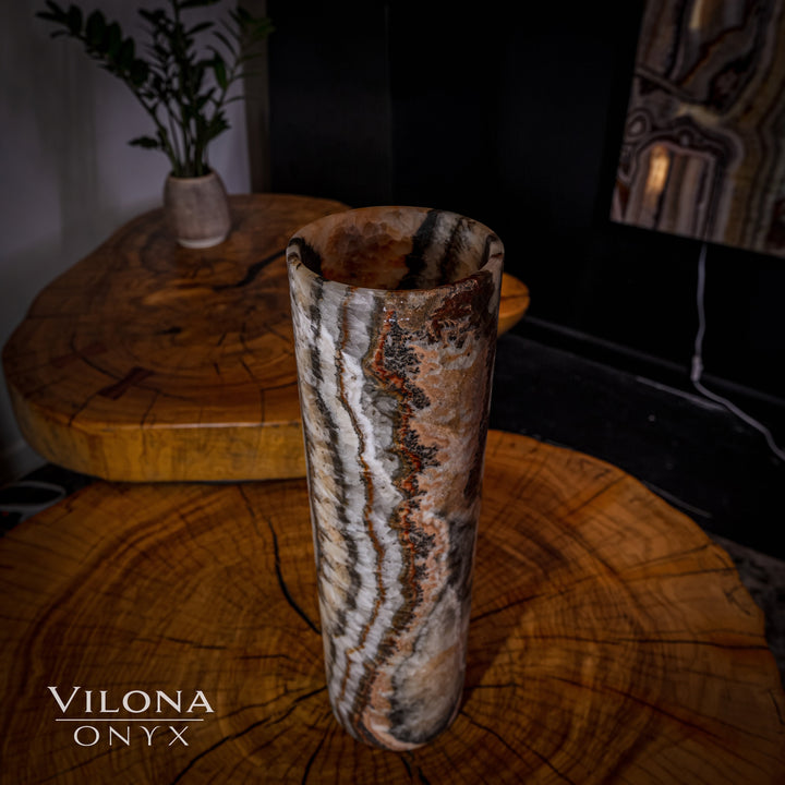 Onyx cylinder table lamp with speckled stone finish and vertical bright white vein lines.