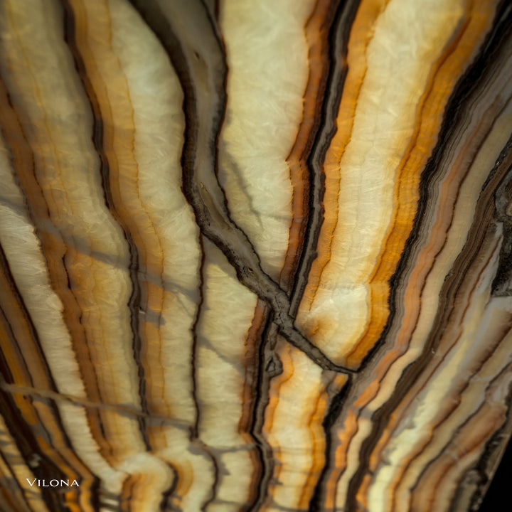 Onyx wall panel texture close-up with cream and gold bands separated by dark lines