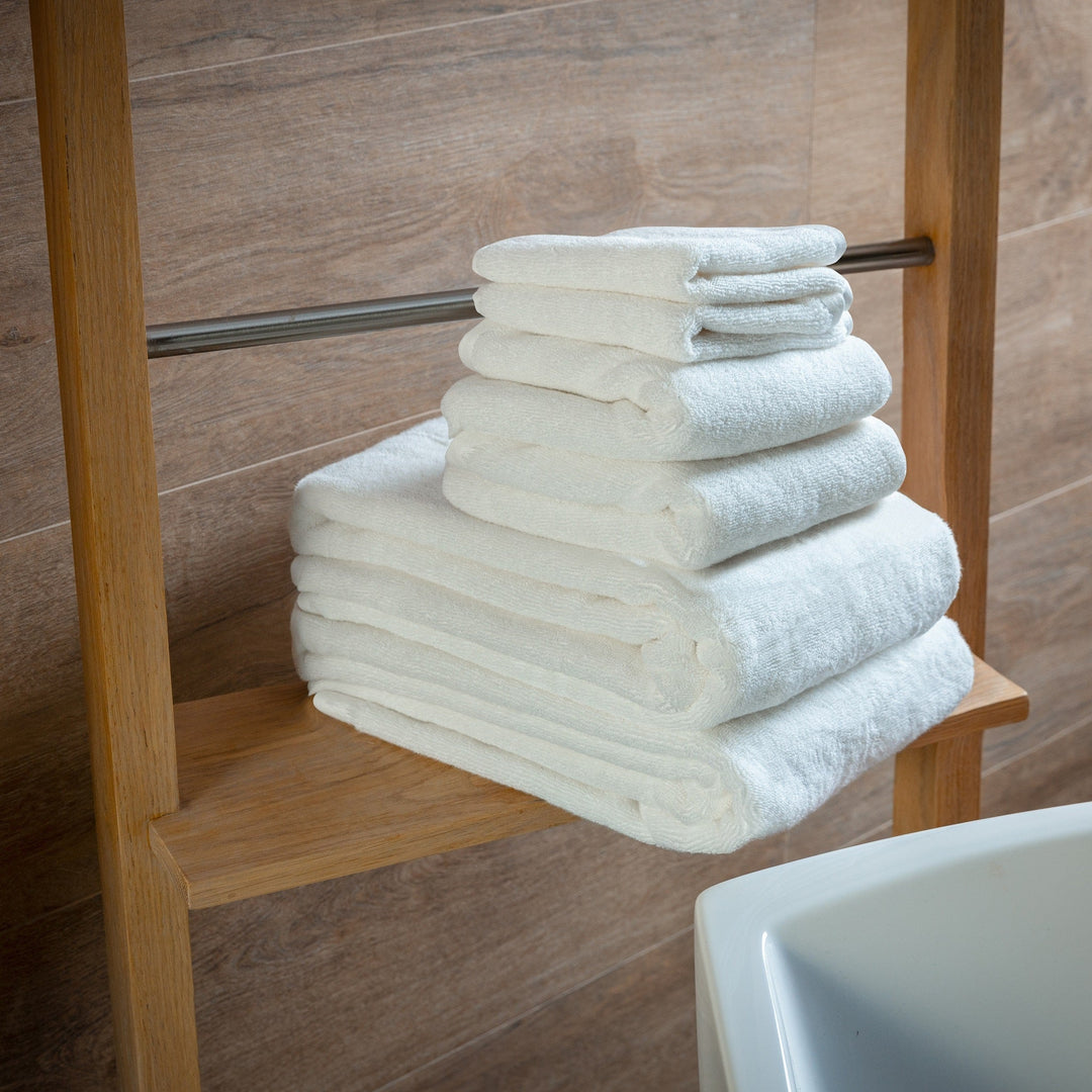 Stack of white bath towels on a wooden bar, neatly folded and ready to use