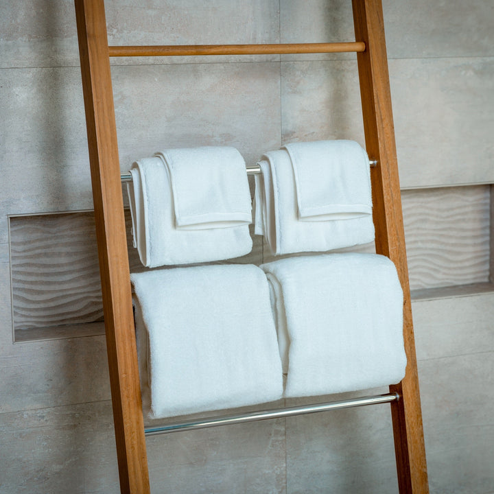 Set of light blue bath towels, folded neatly on wooden ladder rack