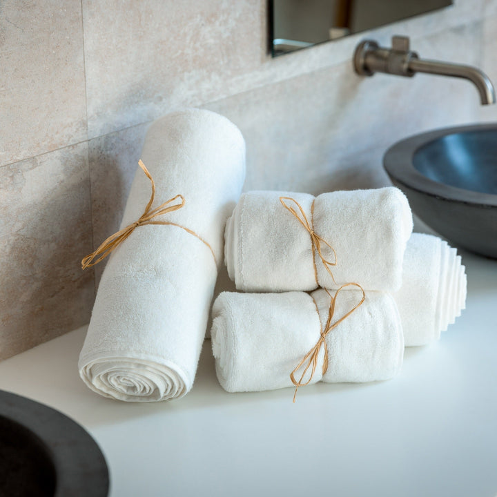 Light blue rolled bath towels tied with orange strings, plush terry texture
