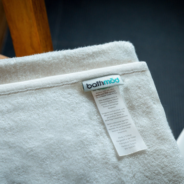 White bath towel with bathmood woven label and care tag on textured fabric