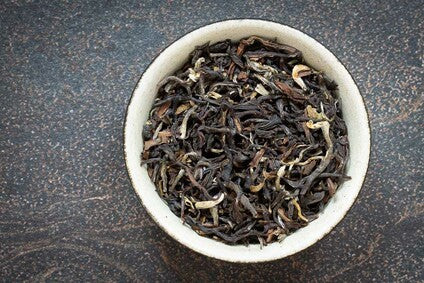 Loose dark tea leaves in a white bowl