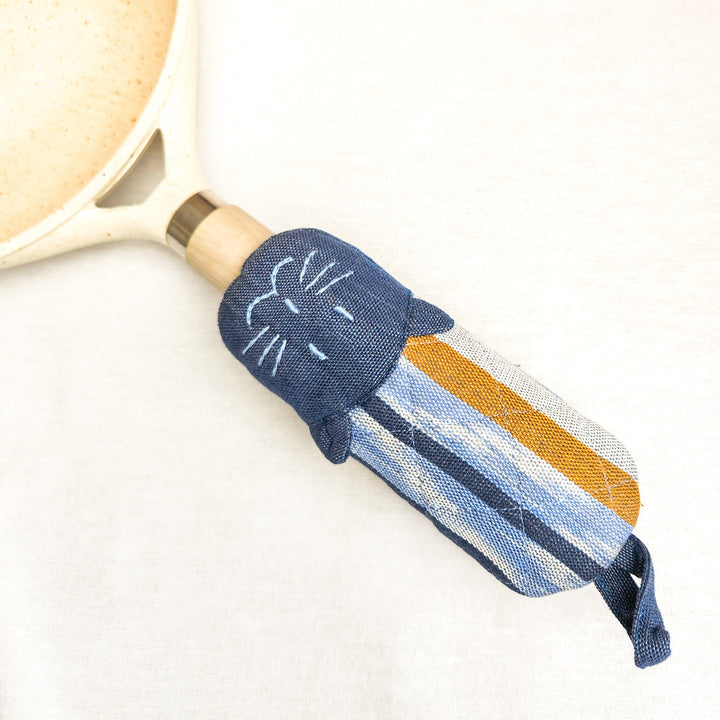 Cat skillet handle holder, navy blue fabric with orange-and-white striped cat face.