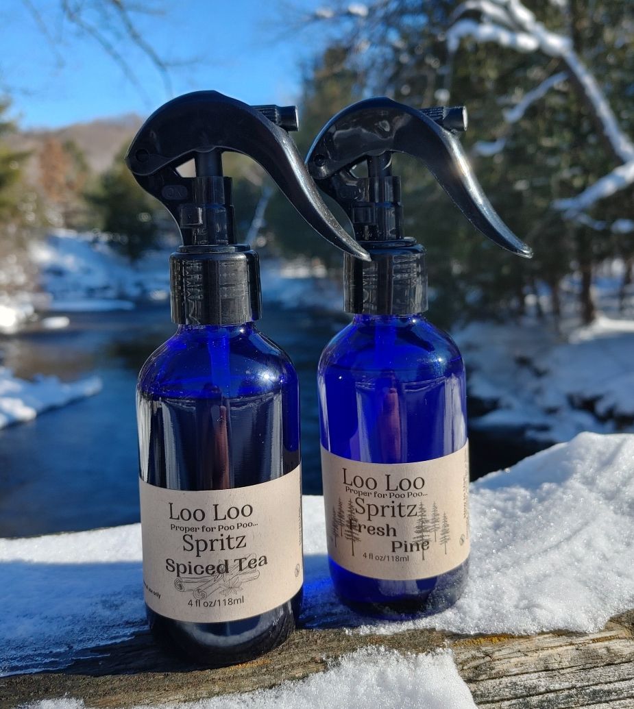 Two deodorizing spray bottles, blue glass with black triggers, Spiced Tea and Fresh Pine