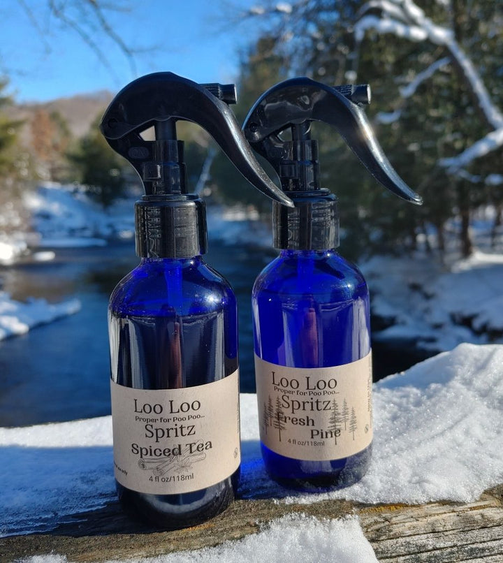 Two deodorizing spray bottles, blue glass with black triggers, Spiced Tea and Fresh Pine