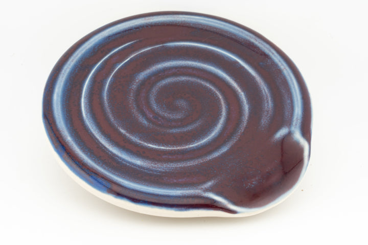 Brown ceramic spoon rest with concentric swirl grooves and raised rim